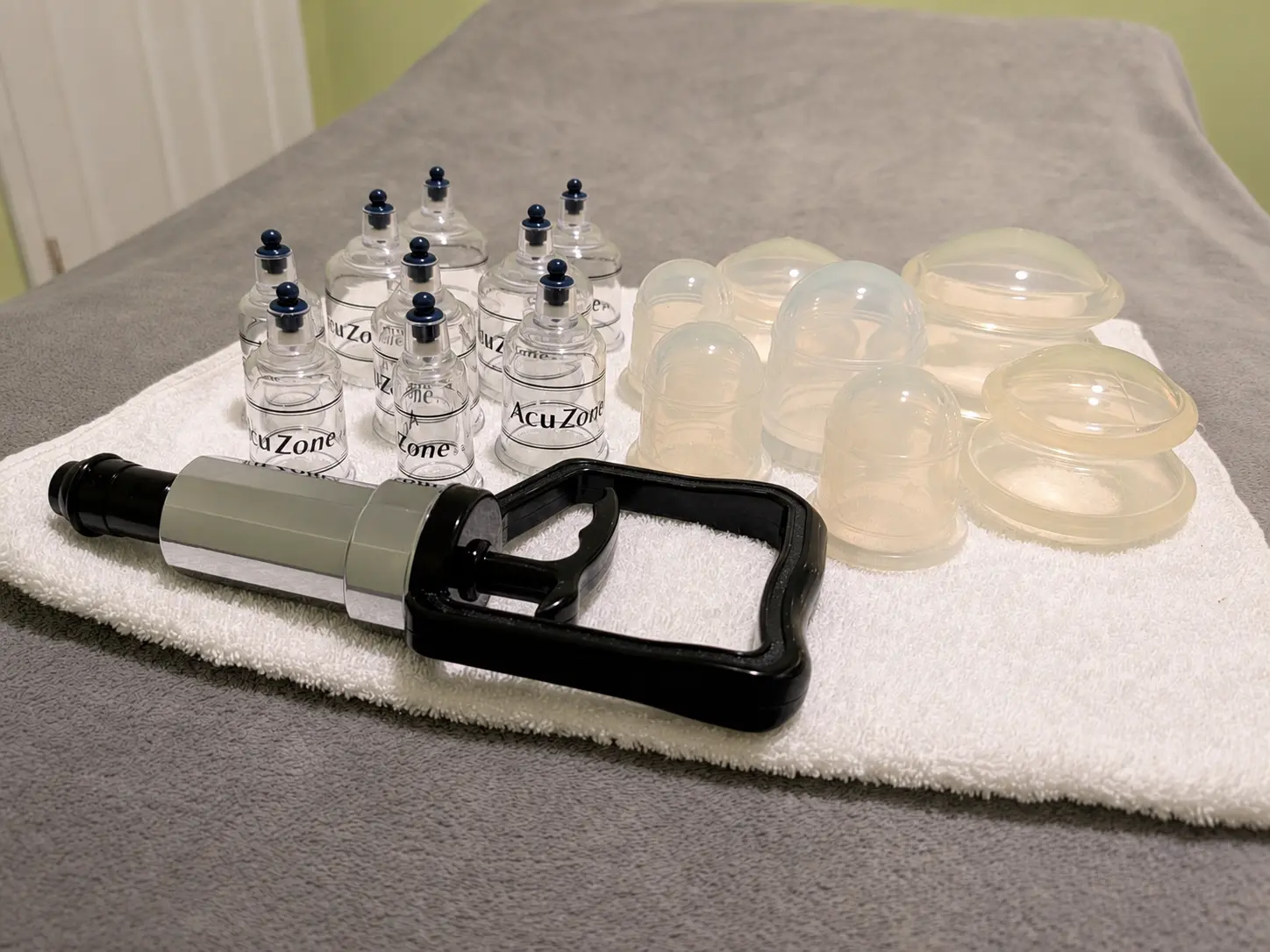 Cupping therapy cups and a handheld suction pump arranged on a massage table.